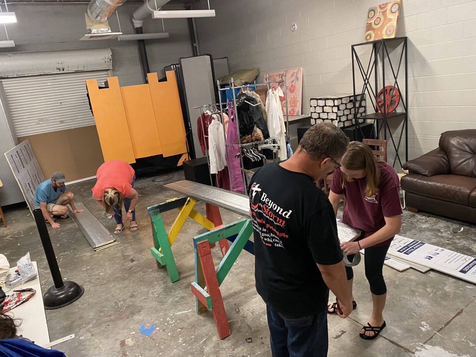 Volunteers working together to build and paint stage set pieces in a workshop space